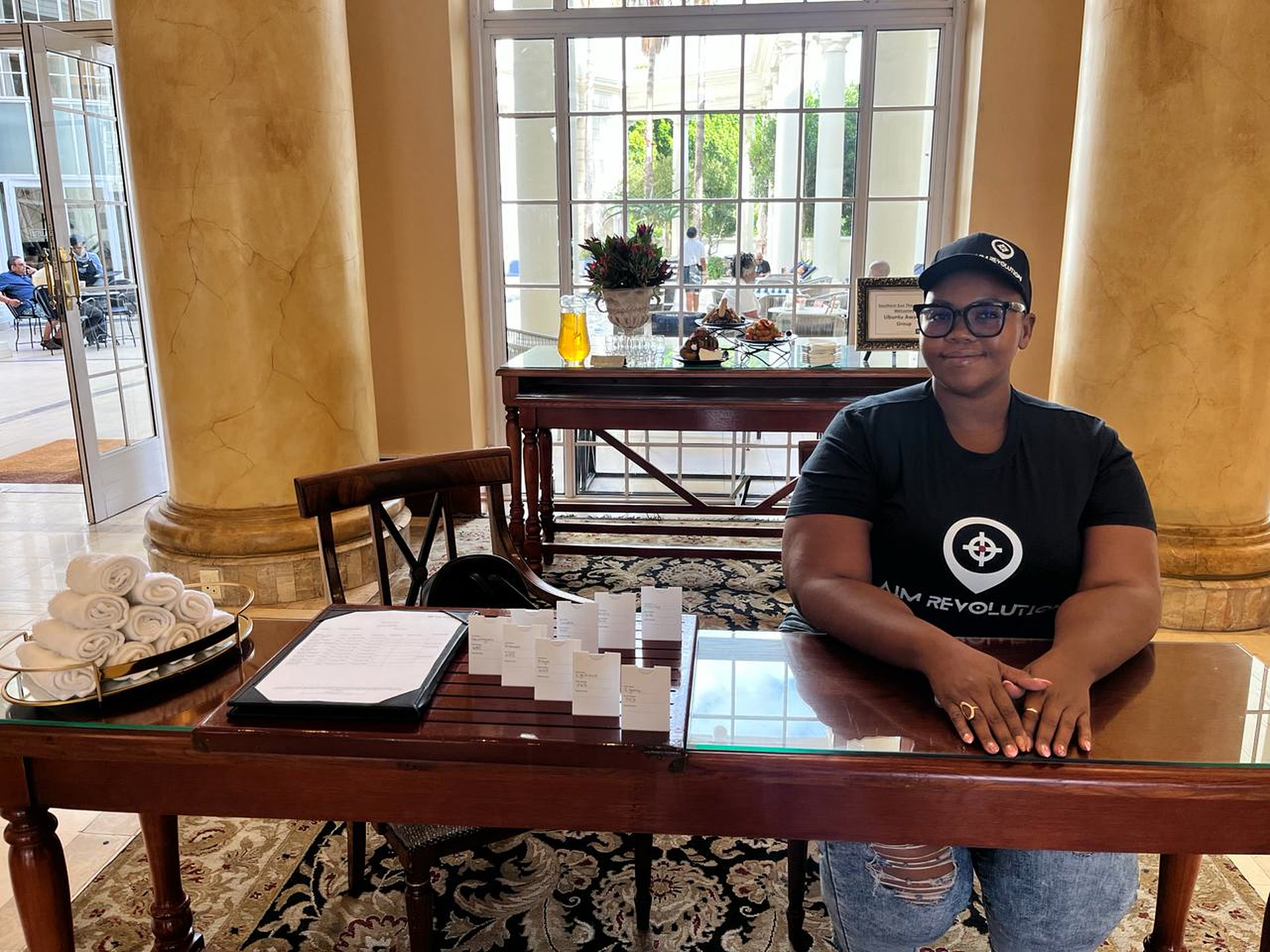 An AIM Revolution team member at a hotel lobby welcome desk with name cards and a guest list