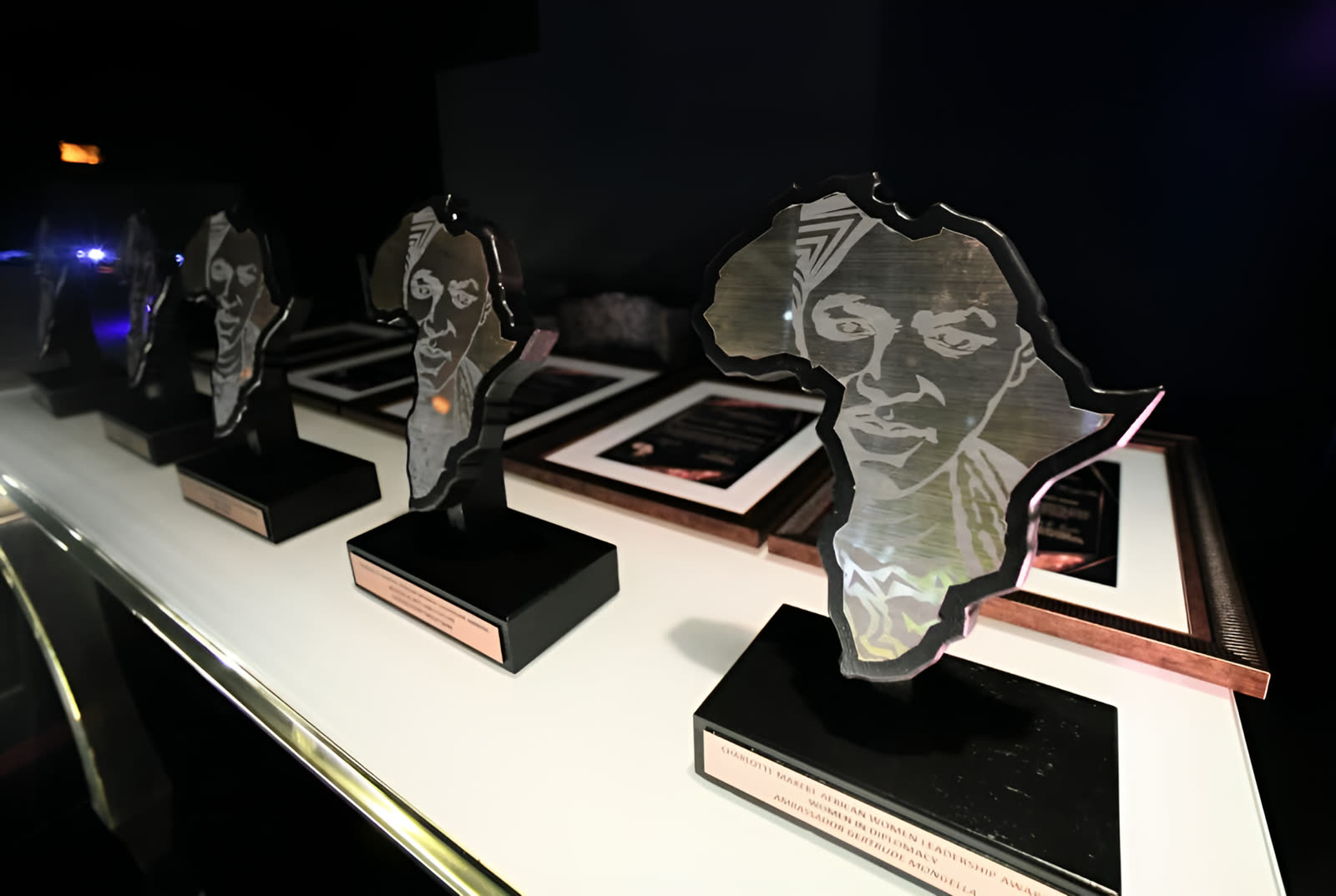 Africa-shaped glass trophies engraved with a portrait, lined up before the awards ceremony